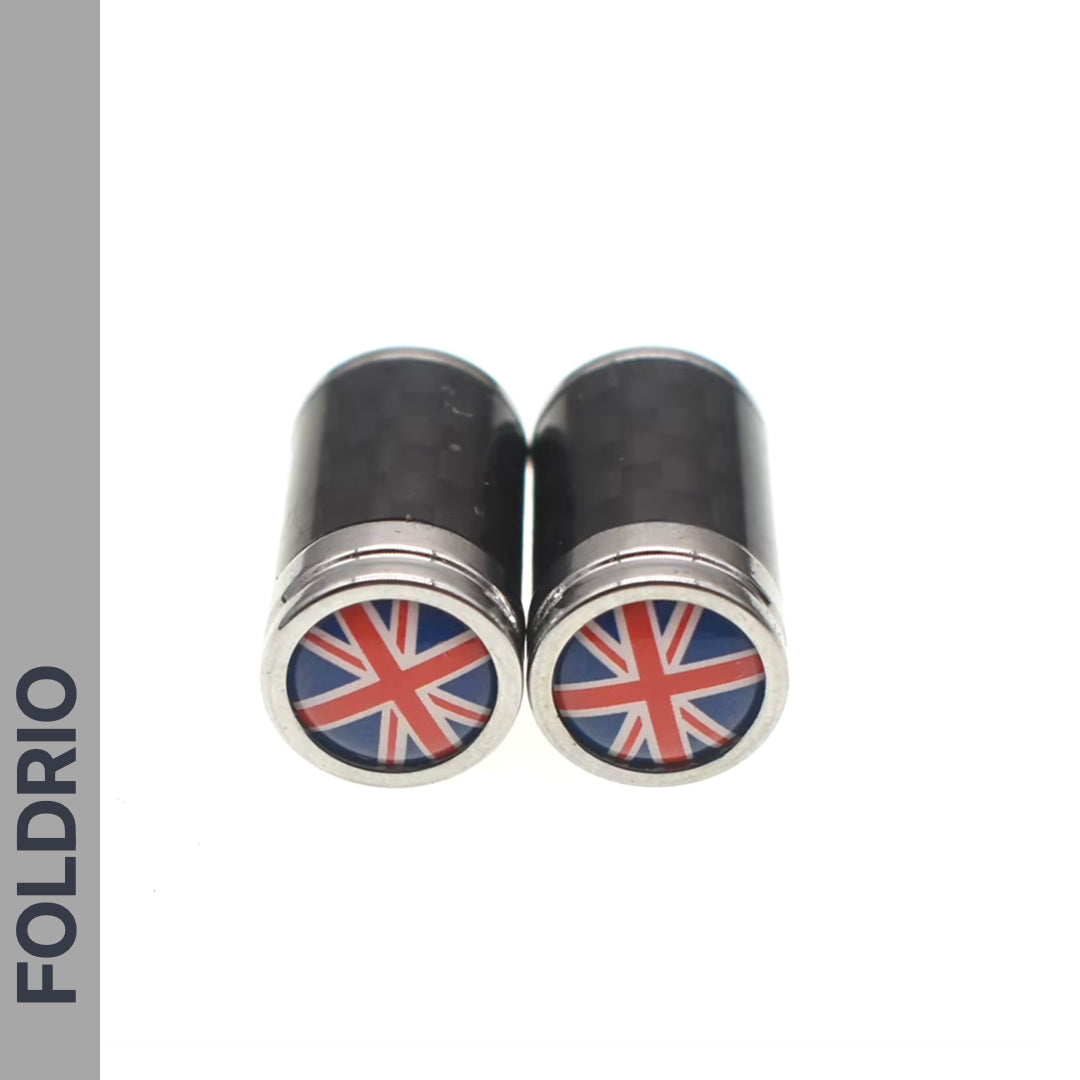 Two black and silver FOLDRIO Brompton Union Jack Valve Caps (Schrader, A/C/G Line) featuring the UK flag on one end are side by side on a white background, with “FOLDRIO” shown vertically along the left edge.