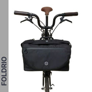 Brompton Brompton S Bag by Foldrio in black mounted on a bike with brown seat and handlebars, logo vertical on the left | Foldrio. Foldrio