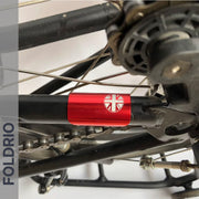 Close-up of a bicycle’s rear wheel, chain, and frame featuring the FOLDRIO Brompton Frame Protector Set with British Flag sticker. "FOLDRIO" appears vertically on the left side.