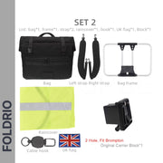 The FOLDRIO Brompton Roll-Top Front Bag – 27.5L includes a laptop compartment, two straps, metal frame, yellow raincover, cable hook, UK flag patch, and original carrier block—compatible with Brompton bikes.