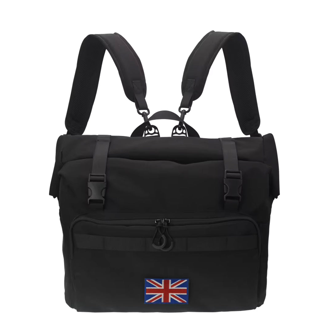 The FOLDRIO Brompton Roll-Top Front Bag – 27.5L is a black laptop and commuter bag with padded shoulder straps, a front pocket, and a United Kingdom flag patch on the lower front.