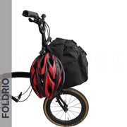 A folding bike with a Brompton Roll-Top Front Bag (27.5L) mounted on the front and a red and black helmet hanging from the handlebars. The FOLDRIO brand name appears vertically on the left side.