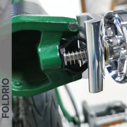 Close-up of a Brompton Stem Fixing Buckle Spring installed on a green bike frame, with shiny silver pedal attachment; the FOLDRIO brand name appears vertically on the left, highlighting this Brompton folding bike accessory.