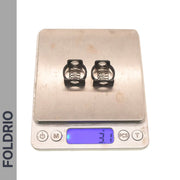 Two small black metal Brompton Stem Fixing Buckle Springs from FOLDRIO are shown on a digital scale reading 3.1 grams, with the “FOLDRIO” brand name displayed vertically on the left side of the image.