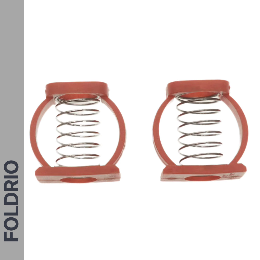 Two Brompton Stem Fixing Buckle Springs by FOLDRIO, each a metal coil spring in a red circular plastic frame, are side by side on a white background. “FOLDRIO” is vertically in bold black letters on a gray strip at the left edge.