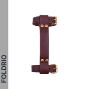 The FOLDRIO Brompton Leather Carry Handle – Full-Grain, Brass Hardware is shown vertically on a white background with FOLDRIO on a gray side strip. It features a brown leather handle, adjustable buckle straps, and brass rivets.