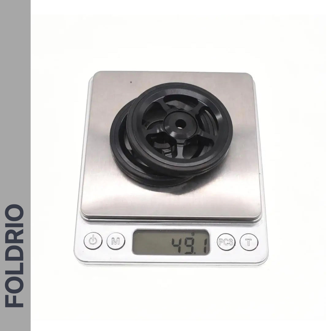 A black plastic pulley labeled FOLDRIO sits on a digital scale at 49.1g—ideal for those upgrading to Brompton Easy Wheels with Titanium Bolts or seeking lightweight alternatives.