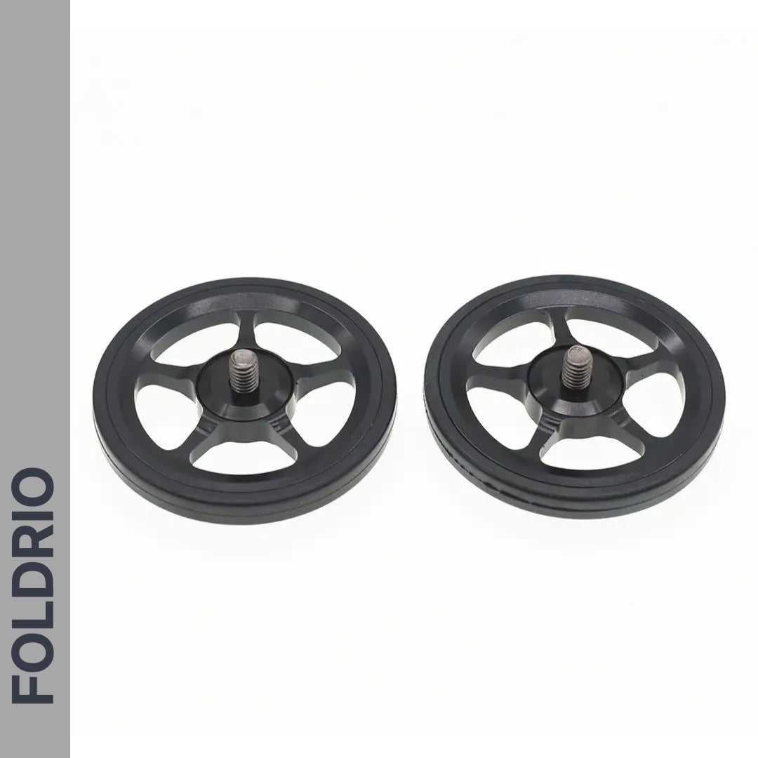 Two black, five-spoke Brompton Easy Wheels with titanium bolts by FOLDRIO are shown side by side on a white background. The brand name appears vertically on a gray strip to the left.