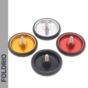 Four circular Brompton Easy Wheels Union Jack Edition by FOLDRIO, in gold, silver, red, and black with titanium bolts, are displayed on a white background. "FOLDRIO" is shown vertically on the left. Perfect for Brompton bikes.