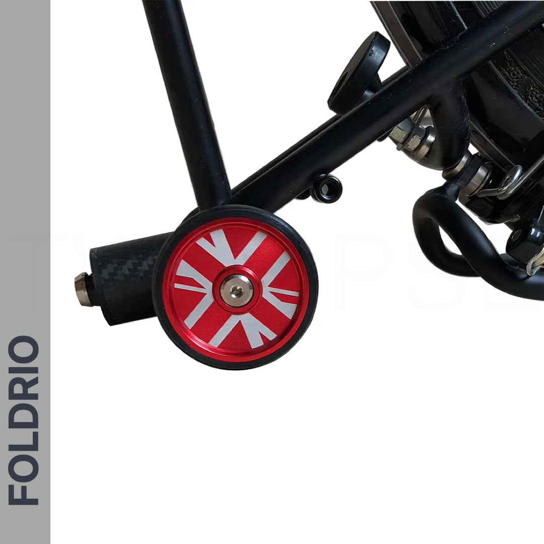 Close-up of FOLDRIO’s Brompton Easy Wheels Union Jack Edition with titanium bolts, crafted from AL7075 aluminium with a red laser-engraved Union Jack, attached to a black carbon fiber frame—compatible with Brompton bikes.
