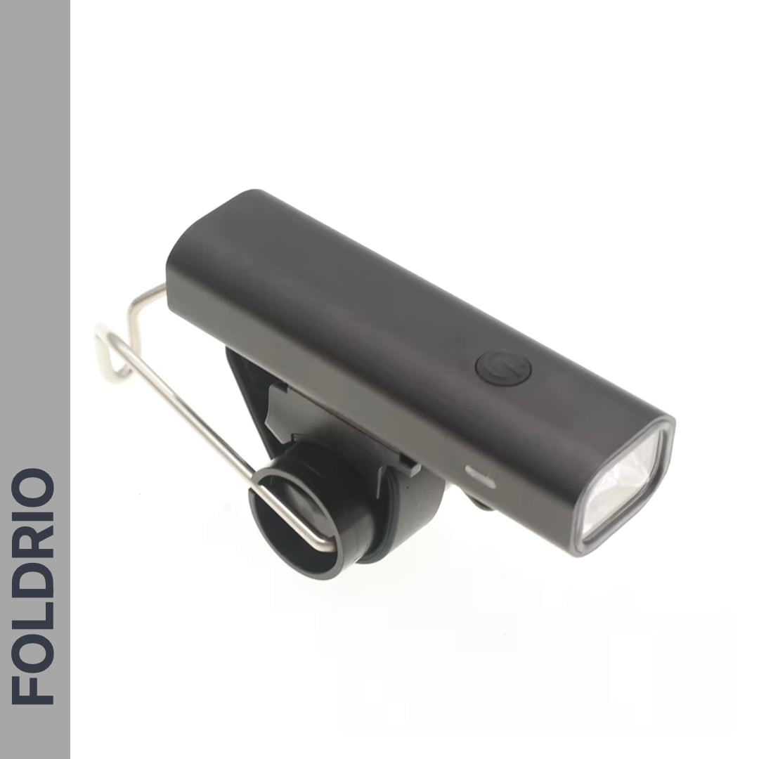 The FOLDRIO Brompton Front Fork Light is a sleek, black, rectangular bike light with 400 lumens brightness, a top power button, and an underside mounting bracket. "FOLDRIO" appears vertically on a gray left sidebar. USB-C rechargeable.