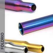 Three metallic, cylindrical Brompton Titanium Seatpost – Multicolour Edition tubes by FOLDRIO are shown in purple-blue, silver, and gold on a white background. The brand name FOLDRIO appears vertically on the left in bold text.