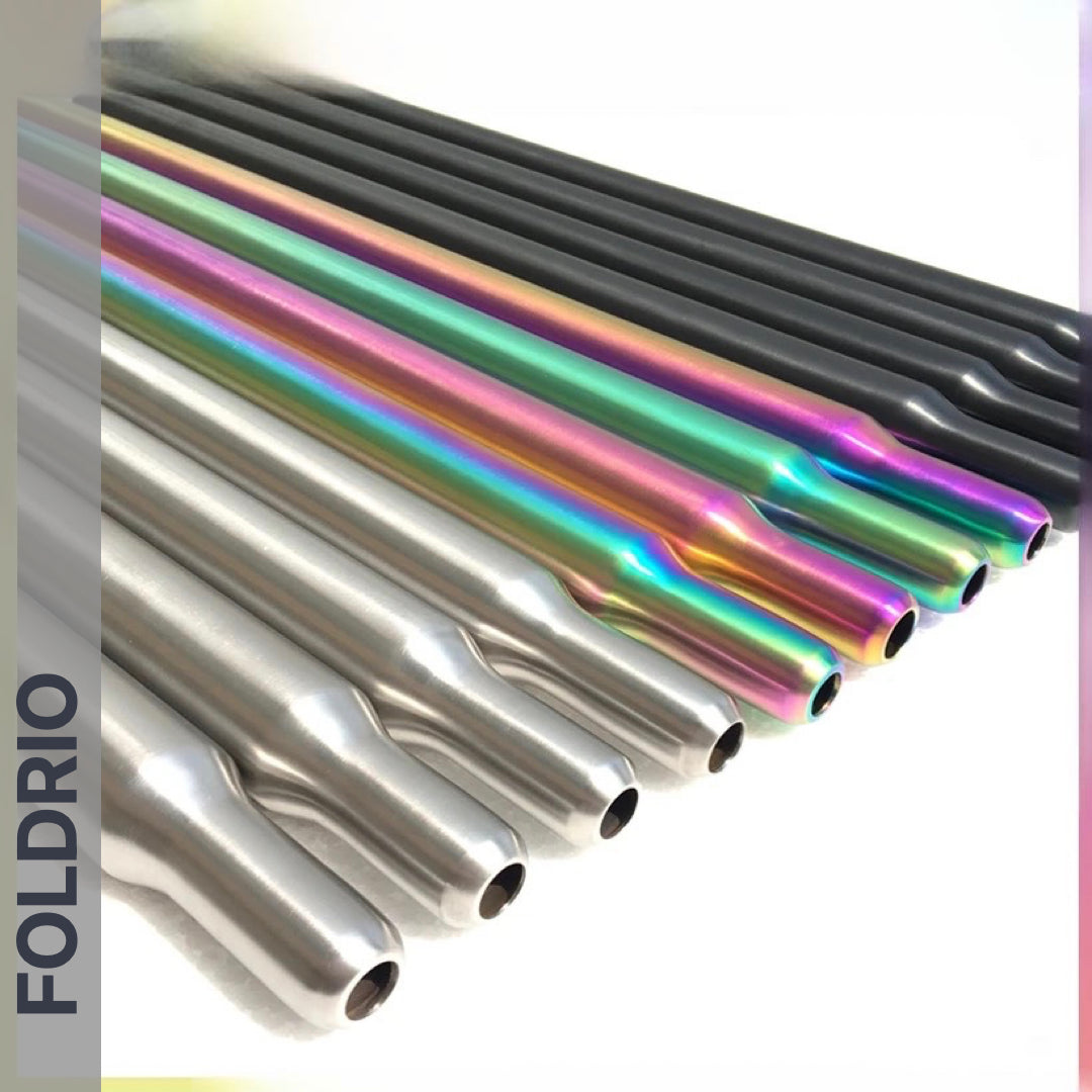 A row of Brompton Titanium Seatposts – Multicolour Edition by FOLDRIO is shown in matte silver, glossy silver, dark gray, and vibrant iridescent finishes, with "FOLDRIO" vertically displayed on the left side.