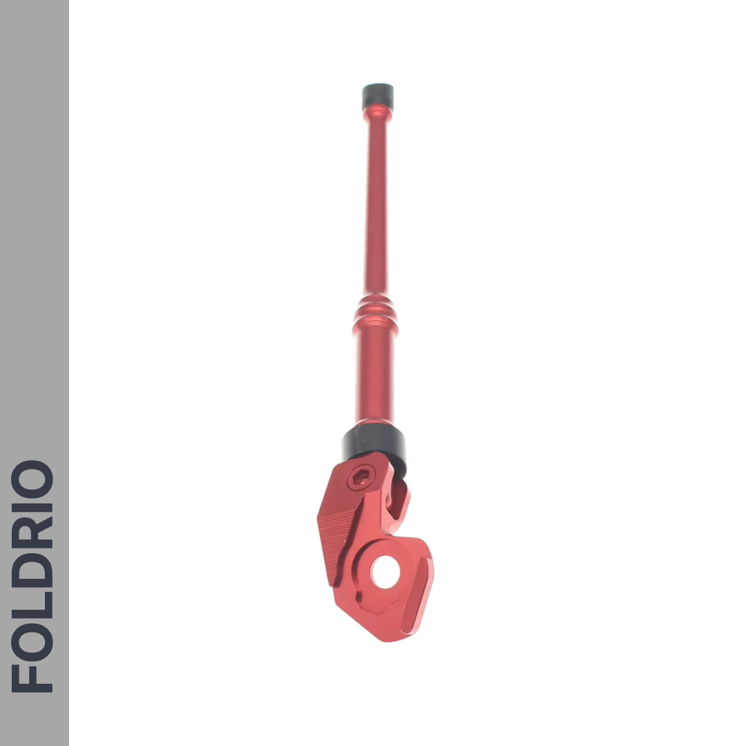 A red FOLDRIO Brompton Kickstand – Adjustable Aluminium for A and C Line bikes is shown vertically on a white background, with "FOLDRIO" in gray along the left. Suitable for rear axle mount setups and features a foldable joint.