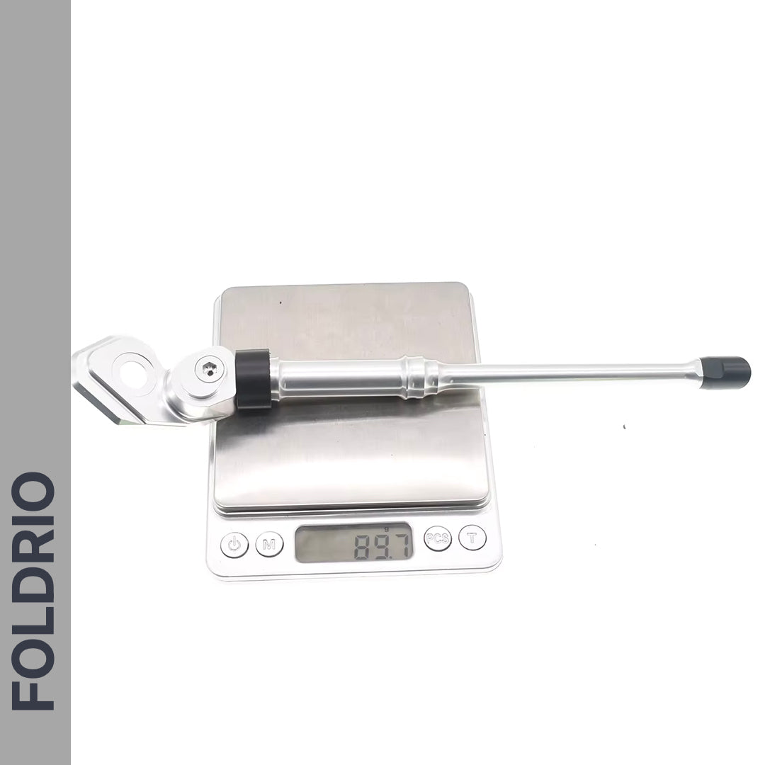 A Brompton Kickstand – Adjustable Aluminium (A and C Line) by FOLDRIO is shown on a digital scale reading 89.7 grams, with the word FOLDRIO displayed vertically on the left side.