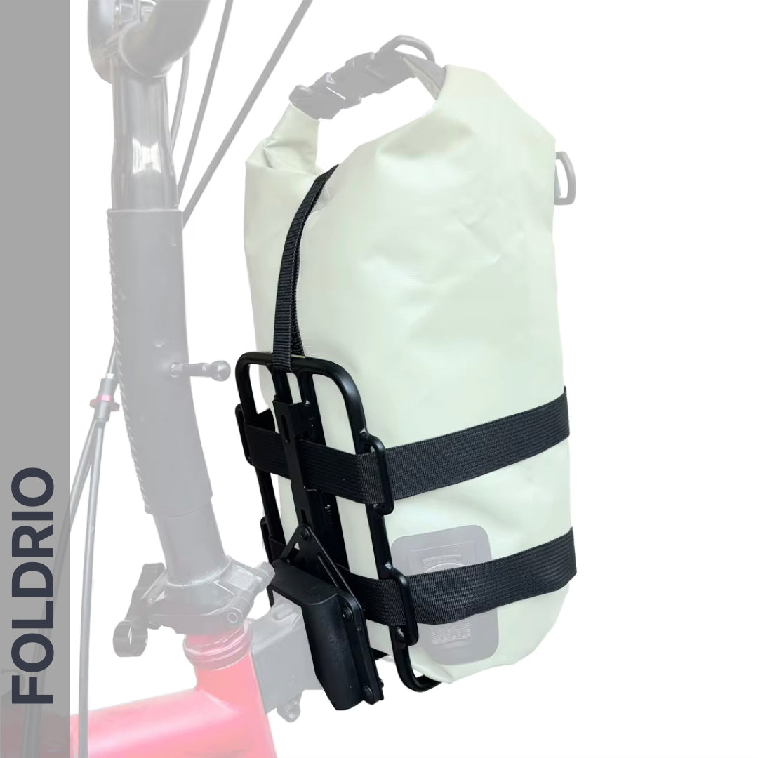A Brompton Folding Bike frame features the FOLDRIO Brompton Front Bag Rack Holder with elastic straps securing a white roll-top dry bag. "FOLDRIO" appears vertically on the left against a mostly white background.