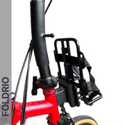Close-up of the FOLDRIO Brompton Front Bag Rack Holder with Elastic Straps mounted on a red bike's handlebar stem; small wheel, cables, and FOLDRIO branding visible—ideal accessory for Brompton folding bikes.