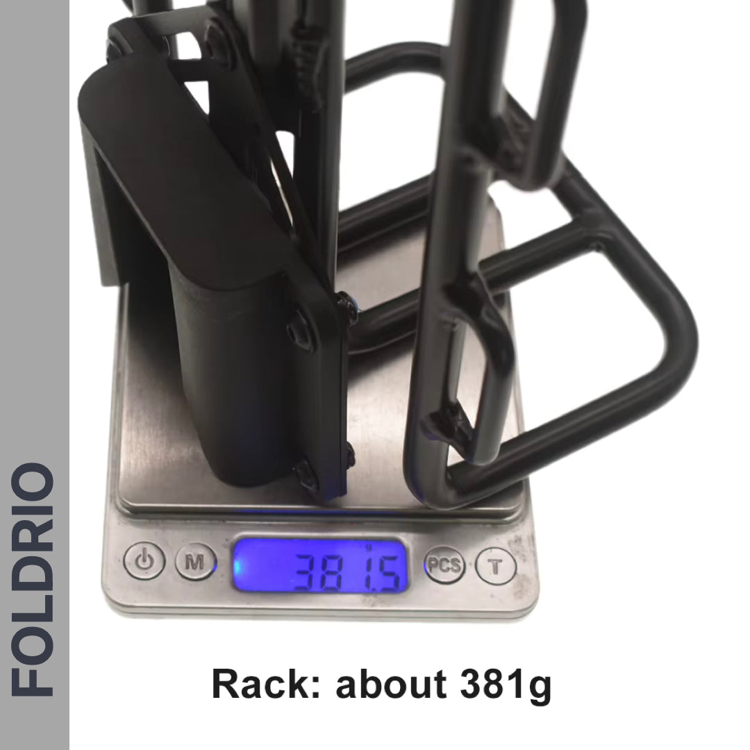 A FOLDRIO Brompton Front Bag Rack Holder with Elastic Straps is shown on a digital scale reading 381.5g, with "FOLDRIO" printed vertically and "Rack: about 381g" below—an ideal accessory for your Brompton.