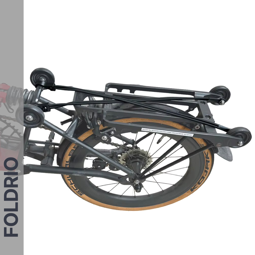 A close-up of a folded bicycle on its side shows tan tires and small wheels secured by FOLDRIO Brompton Rear Rack Elastic Straps (fits AC Line & PT Line), set against a white background with "FOLDRIO" written vertically on the left.