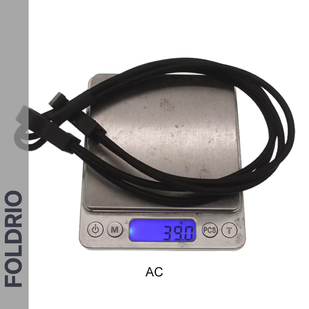 A coiled Brompton Rear Rack Elastic Strap by FOLDRIO, for AC Line (old) & PT Line (new), sits on a digital scale reading 39.0 grams. "FOLDRIO" is shown vertically at left; "AC" is labeled beneath the scale.
