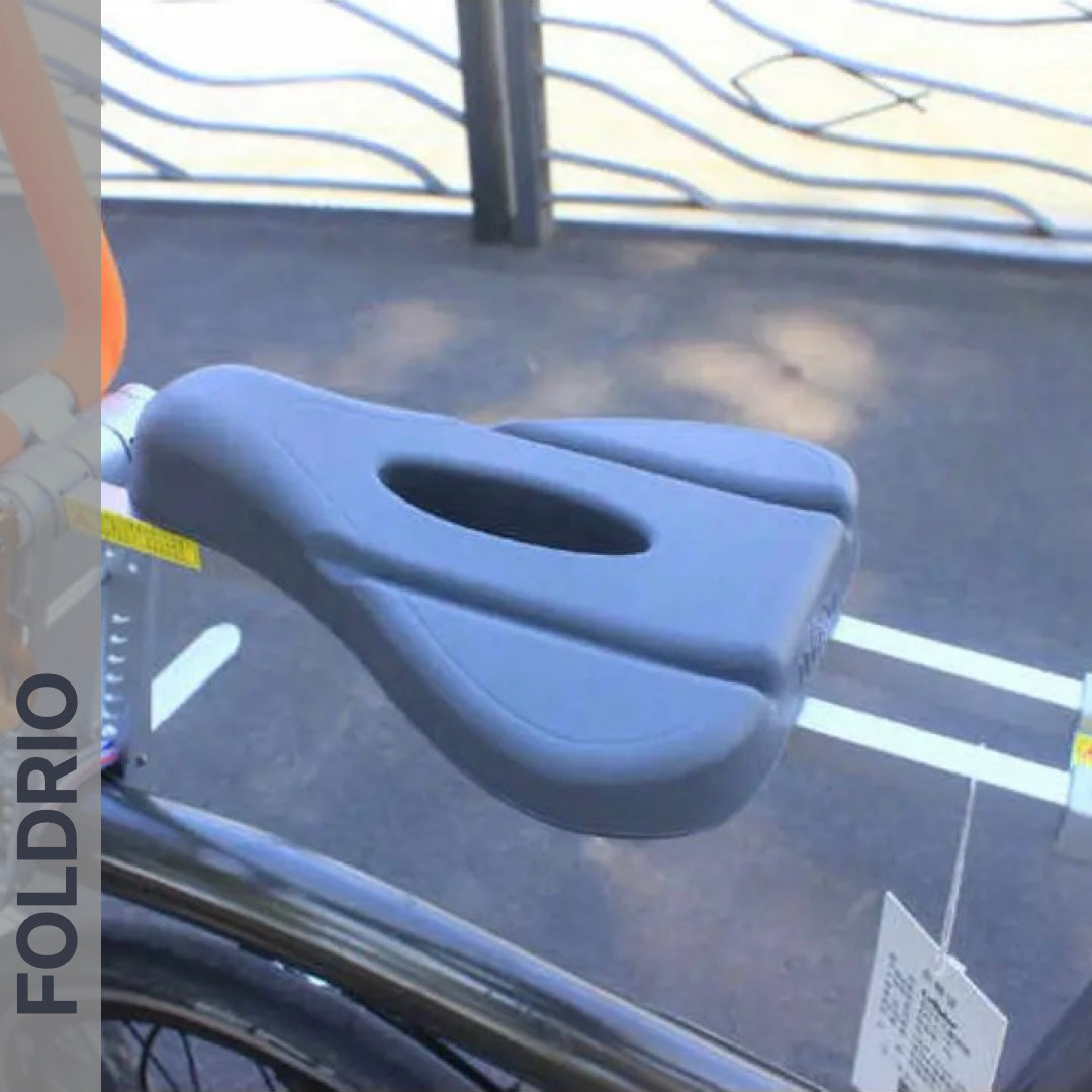 Brompton Brompton gray ergonomic seat with center cutout on Foldrio front child mount, safety bar visible, wavy metal fence behind | Foldrio. Foldrio