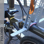 Brompton Brompton-compatible folding bike frame featuring a silver lock for child seat; walkway and rail behind | Foldrio. Foldrio