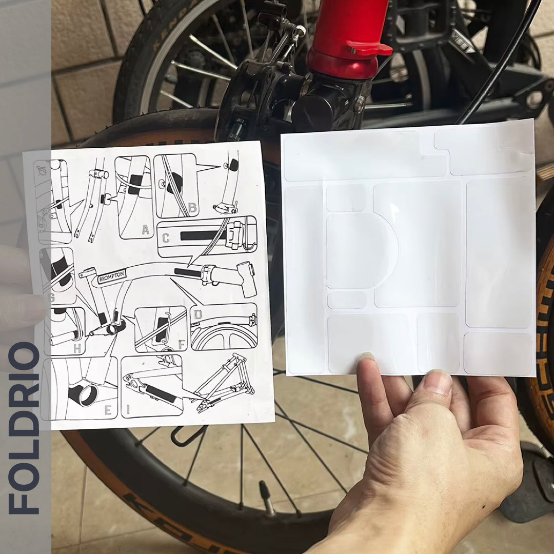 Brompton Brompton protective sticker set and instructions held before red frame and wheel, FOLDRIO branding vertical at left | Foldrio. Foldrio