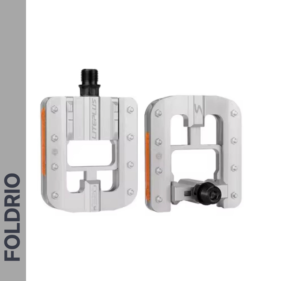 Two Brompton Foldable Flat Pedals – Lightweight Aluminium Upgrade, silver with black axles and reflective orange strips, featuring a rectangular open design, are shown on a white background. FOLDRIO appears vertically on the left. Ideal Brompton replacement.